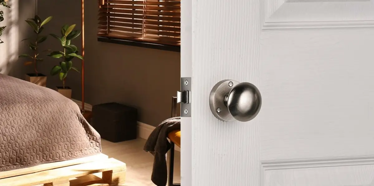 a brushed nickel door knob on a white wooden door