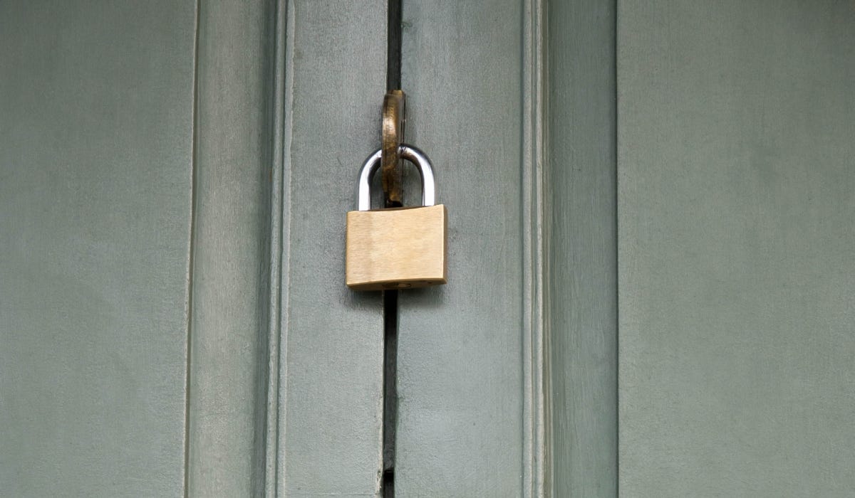 brass padlock on a green door